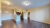 This single-floor residence offers a thoughtfully designed open layout with consistent warm, neutral tones throughout. The main living area is anchored by rich, dark hardwood flooring that extends across the open-concept space, complemented by crown molding and a neutral color palette. A glass-paneled door brings in natural light and provides exterior access, enhancing the airy feel of the living space.

The kitchen is a functional centerpiece, defined by a peninsula breakfast bar with pendant lighting overhead. Dark espresso cabinetry reaches toward the ceiling, paired with granite-style countertops and a classic white subway tile backsplash. Stainless steel appliances — including a range, over-the-range microwave, dishwasher, and refrigerator — complete the space. An elegant arched passageway connects the main living area to a dedicated in-unit laundry alcove, which houses a full-sized washer and dryer with overhead shelving.

The bedroom features plush carpeting, two generously sized windows that invite natural light, and ample wall space. The bathroom includes a wide vanity with granite-style countertops, dark cabinetry with brushed nickel hardware, a large mirror, and a tub-shower combination.