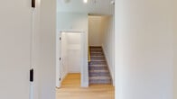 Located at 1542 Spur Dr S in Islip, New York, this two-story home presents a clean, modern aesthetic with thoughtfully selected finishes across both levels. The main floor features light hardwood flooring that flows through the open living areas and into the kitchen. The kitchen is a standout space, designed with two-tone cabinetry—sleek white upper cabinets paired with warm wood-finish lower cabinets—topped with white quartz countertops. A large center island provides additional workspace and casual seating, while stainless steel appliances, including a gas range, built-in microwave, dishwasher, and refrigerator, complete the setup. Industrial-style pendant lighting adds a contemporary touch overhead. A half bath on the main level features a floating wood-tone vanity with a white quartz top and a framed mirror. Carpeted staircase leads to the upper level, where bedrooms offer plush carpet flooring and natural light through blinds-fitted windows. A dedicated walk-in closet serves one of the bedrooms. The upper-level full bathroom is finished with marble-look tile flooring, a wide dual-sink vanity with white countertops, and ample cabinetry. Additional under-stair storage is also accessible, adding practical utility to the well-organized layout.
