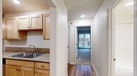 This efficiently designed one-bedroom, one-bathroom unit offers a thoughtful single-floor layout that maximizes functionality. The combined kitchen and living area forms the heart of the unit, where light wood laminate flooring flows seamlessly throughout. The kitchen is well-equipped with light maple cabinetry offering generous storage, granite-style countertops, a double stainless steel sink, and a full suite of stainless steel appliances including a range, microwave, and refrigerator. A ceiling fan provides additional comfort in the adjoining living area, which opens to a private balcony through a sliding glass door, bringing in natural light and outdoor views.

A hallway connects the main living area to the bedroom, which features plush carpeting, a closet, and a textured ceiling. The neutral color palette throughout creates a calm, cohesive atmosphere. The bathroom includes a full tub-shower combination with chrome fixtures, a light maple vanity with granite-style countertops, and a large mirror. Hardwood-style flooring in the main areas and carpet in the bedroom provide both practicality and comfort across this well-maintained unit.