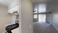 This single-story unit is designed with a practical, open layout that connects the main living and kitchen areas seamlessly. The living room is generously sized, finished with neutral-toned carpet and anchored by a ceiling fan with a light fixture. Large sliding glass doors fitted with vertical blinds allow ample natural light to fill the space and provide access to an outdoor area. A pass-through window connects the living room to the kitchen, enhancing the open feel between the two spaces.

The kitchen features a galley-style configuration with wood-look vinyl plank flooring, white cabinetry, and speckled granite-style countertops. Stainless steel appliances include a gas range and dishwasher, complemented by an under-cabinet range hood and a double-basin sink positioned beneath a window.

The bedrooms are carpeted and finished in soft neutral tones, each featuring windows with vertical blinds that bring in natural light. The bathroom is appointed with wood-look vinyl plank flooring, a white vanity with granite-style countertops, and a tub-shower combination with a curved curtain rod. Clean white walls and crisp finishes give the bathroom a bright, functional character throughout.
