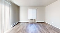 This 570 square foot apartment in Fox Crossing, WI, offers a well-designed living space with modern amenities. The single-floor layout comprises one bedroom, one bathroom, and an open-concept living area. Throughout the apartment, wood-look flooring adds warmth and continuity.

The bedroom, measuring 140 square feet, provides ample space for a comfortable sleeping area. It features a built-in closet with shelving for organized storage. The bathroom is efficiently designed with a white tub-shower combination, toilet, and vanity with a granite-look countertop.

The main living area is bright and airy, with white walls that reflect natural light from the windows. A wall-mounted air conditioning unit ensures year-round comfort. The space is versatile, allowing for a combined living and dining arrangement. Built-in shelving in the living area offers additional storage or display options.

The kitchen, while not visible in the images, is likely integrated into the open floor plan. The apartment's layout maximizes the use of space, making it ideal for single occupants or couples seeking an efficient living environment. The neutral color palette and clean lines create a contemporary feel, providing a blank canvas for personal decorating styles.