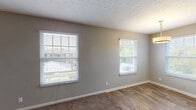 This single-story, two-bedroom, one-bathroom unit in Louisville, Kentucky offers a practical and well-appointed layout across a comfortable footprint. The living area serves as the central gathering space, featuring a combination of wood-look plank flooring and carpet, neutral gray walls, and a textured ceiling. Multiple windows fitted with horizontal blinds allow natural light to fill the room while providing views of the surrounding exterior.

Both bedrooms are carpeted and finished with the same neutral gray palette, each equipped with a ceiling fan and light fixture. Windows in each bedroom offer additional natural light and ventilation. The rooms provide ample wall space suitable for varied furniture arrangements.

The kitchen is outfitted with white cabinetry, granite-style countertops, a subway tile backsplash, stainless steel appliances including a range and over-the-range microwave, and wood-look flooring that extends throughout the space. The clean, bright design gives the kitchen a modern, functional character.

The bathroom is a notable highlight, featuring a full tub and shower combination surrounded by large-format marble-look tiles with gold-toned hardware. A window above the tub adds natural light, enhancing the upscale feel of the space. White trim and baseboards throughout the unit provide a cohesive, polished finish.