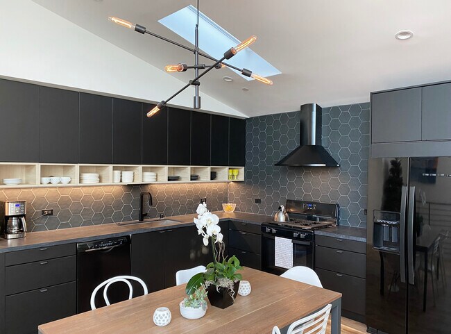Chef's Kitchen with black stainless steel appliances, tile backsplash, quartz countertops, skylight. - 10815 Oregon Ave