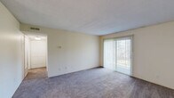 Located at 410 Charity Circle in Lansing, Michigan, this one-bedroom, one-bathroom unit offers a well-organized single-floor layout designed for comfortable everyday living. The combined kitchen and living area forms the heart of the unit, with the spacious carpeted living room featuring a sliding glass door that fills the space with natural light and provides outdoor views. A dedicated entry door with an overhead light fixture opens directly into this open area. The galley-style kitchen is efficiently laid out with warm wood cabinetry lining both sides, offering ample storage above and below the counters. It includes a double stainless steel sink, white appliances—including a coil-top electric range and full-size refrigerator—and light tile flooring that contrasts neatly with the carpeted living areas. The bedroom is a well-proportioned retreat featuring plush carpet, neutral walls, and two windows fitted with vertical blinds that invite natural light. A door from the bedroom connects to a closet and the hallway for convenient access throughout the unit. The bathroom is clean and functional, featuring a full-size soaking tub with an integrated shower surround in crisp white. A hallway connects all rooms, adding to the efficient and practical flow of the layout.