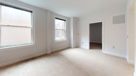 Located at 101 W Read St in Baltimore's vibrant Mount Vernon neighborhood, this single-floor unit offers a thoughtfully laid-out interior with a clean, neutral aesthetic throughout. The generously sized living area is finished with plush wall-to-wall carpeting and crisp white walls, creating a bright and inviting atmosphere. Multiple double-hung windows allow natural light to filter in, with views of the surrounding urban streetscape. A pass-through opening connects the living space to the kitchen, enhancing the sense of openness and flow. The galley-style kitchen is well-appointed with light wood cabinetry, dark countertops, and hardwood-style flooring, providing ample counter and storage space along both sides of the corridor. A stainless range anchors one end of the kitchen, making it both functional and practical. The bedroom is carpeted and generously proportioned, with large windows that continue the theme of natural light, and access to a dedicated closet space. The full bathroom features classic penny-tile flooring in a neutral tone, a wood-vanity with a single sink, a large mirror, and clean, understated finishes throughout. The overall ambiance is calm and move-in ready, well-suited for urban living in the heart of Baltimore.