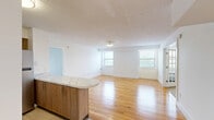 Located at 1317 East St in New Britain, CT, this well-appointed 1-bedroom, 2-bathroom residence offers a thoughtfully designed single-floor layout. The heart of the home is an open-concept kitchen and living area, where warm hardwood flooring extends throughout, creating a bright and cohesive space. The kitchen features walnut-toned cabinetry, stainless steel appliances including a refrigerator, range, microwave, and dishwasher, and light-colored countertops. A curved, marble-top island serves as a stylish divider between the kitchen and the expansive living room, which is bathed in natural light from multiple windows. The spacious bedroom is finished with plush carpeting and includes two windows that bring in additional natural light, along with generous closet storage — three closets total are found throughout the unit. Both bathrooms are finished with white tile flooring; one features a wood-toned vanity with a mirrored medicine cabinet and a combination tub/shower, while the second offers a clean, all-white aesthetic with a tub/shower combo. A hallway connects the main living spaces to the private areas of the home. The textured ceiling and clean white walls throughout lend a crisp, move-in-ready appearance to this efficiently designed residence.