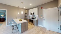 This well-appointed 2-bedroom, 2-bathroom residence at Somerville Parc in Somerville, NJ delivers a thoughtfully designed single-floor layout with contemporary finishes throughout. Light-toned hardwood-style flooring flows through the main living areas, creating a cohesive and modern aesthetic.

The kitchen is a standout feature, showcasing a two-tone cabinetry design with wood-grain lower cabinets and crisp white uppers, stainless steel appliances including a refrigerator, range, and microwave, and a white quartz peninsula with bar seating. Pendant lighting adds a refined touch above the countertop.

The living area benefits from large windows that invite natural light and offer outdoor views, complementing the warm, neutral wall tones. Both bedrooms are generously proportioned, with one featuring bold teal accent walls, a walk-in closet, and direct sightlines to the kitchen. The second bedroom features large windows with community views.

The two bathrooms are distinctly finished: one offers a sleek walk-in glass-enclosed shower with textured wave-pattern tile, while the other features a floating vanity, framed mirror, and a tub-shower combination with elegant marble-style surround tile. Together, these spaces offer a comfortable, contemporary living experience in a well-planned layout.