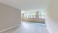 Located at 345 Merton Street in Toronto's vibrant Davisville Village neighbourhood, this well-appointed one-bedroom, one-bathroom unit offers a thoughtfully designed layout across a single floor. Light-toned hardwood flooring flows throughout the living and bedroom areas, creating a bright and cohesive feel.

The spacious living room is a standout feature, lined with a wide bank of floor-to-near-ceiling windows that flood the space with natural light and frame lush, mature greenery outside — a rare and serene urban outlook. Baseboard heating runs along the perimeter, ensuring year-round comfort.

The bedroom is generously proportioned, offering ample space for furnishings, and includes a built-in sliding door closet for practical storage. Its neutral, warm-toned walls complement the light flooring for a calm, restful atmosphere.

The bathroom is elegantly finished with large-format marble-effect wall tiles surrounding a full soaker tub and shower combination, adding a refined touch to the space. A small window provides natural ventilation.

The kitchen is efficiently laid out with white cabinetry, tiled flooring, and a full-size stainless steel refrigerator. It connects seamlessly to the entryway, which features a solid front door and additional storage. Overall, this unit presents a clean, modern aesthetic with functional design throughout.