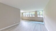 Located at 345 Merton Street in Toronto's vibrant Davisville Village neighbourhood, this well-appointed one-bedroom, one-bathroom unit offers a thoughtfully designed layout across a single floor. Light-toned hardwood flooring flows throughout the living and bedroom areas, creating a bright and cohesive feel.

The spacious living room is a standout feature, lined with a wide bank of floor-to-near-ceiling windows that flood the space with natural light and frame lush, mature greenery outside — a rare and serene urban outlook. Baseboard heating runs along the perimeter, ensuring year-round comfort.

The bedroom is generously proportioned, offering ample space for furnishings, and includes a built-in sliding door closet for practical storage. Its neutral, warm-toned walls complement the light flooring for a calm, restful atmosphere.

The bathroom is elegantly finished with large-format marble-effect wall tiles surrounding a full soaker tub and shower combination, adding a refined touch to the space. A small window provides natural ventilation.

The kitchen is efficiently laid out with white cabinetry, tiled flooring, and a full-size stainless steel refrigerator. It connects seamlessly to the entryway, which features a solid front door and additional storage. Overall, this unit presents a clean, modern aesthetic with functional design throughout.