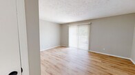 Located in Indianapolis, IN 46260, this well-appointed 2-bedroom, 2-bathroom single-floor residence offers a clean, updated aesthetic throughout. The living room is a bright, open space featuring light wood-look plank flooring, neutral gray walls, a textured ceiling, and a sliding glass door dressed with vertical blinds that floods the room with natural light. The entry area echoes the same warm flooring and understated palette, providing a welcoming transition into the home. The kitchen is a standout feature, showcasing crisp white shaker cabinets, white quartz countertops, a classic subway tile backsplash, and black appliances including a range, microwave, and dishwasher. A full-size stacked washer and dryer unit is conveniently integrated within the kitchen area. Both bedrooms are carpeted and bathed in natural light from windows with outdoor views, offering a comfortable and quiet retreat. The primary bedroom is generously sized with ample room for furnishings. The two bathrooms are tastefully finished — one features a white vanity with a quartz countertop, black fixture accents, a framed mirror, and pendant lighting, while the second includes a full soaking tub/shower combo with clean white tile surround and matching black hardware throughout.