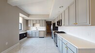 Located in the heart of downtown Columbus at 50 W Broad St, this single-floor residence offers a thoughtfully designed layout with upscale finishes throughout. The spacious kitchen is a standout feature, showcasing floor-to-ceiling grey cabinetry with gold hardware, white quartz countertops, a white subway tile backsplash, and stainless steel appliances including a gas range, built-in microwave, refrigerator, and dishwasher. Large-format marble-look porcelain tile floors add a polished, cohesive aesthetic to the kitchen and adjoining areas.

The bedrooms feature neutral-toned carpet and windows with roller shades that frame elevated views of the Columbus skyline. Built-in ledge detailing along the windows provides an architectural accent. Each bedroom is complemented by a generously sized walk-in closet outfitted with wire shelving systems and carpeted flooring for practical storage.

Two full bathrooms serve the residence. One features a soaking tub with marble-surround tile and a sage-toned vanity, while the other offers a walk-in marble tile shower with glass enclosure and a light grey vanity with quartz countertop. Both bathrooms include warm-toned tile flooring. The overall ambiance is clean, modern, and polished throughout.