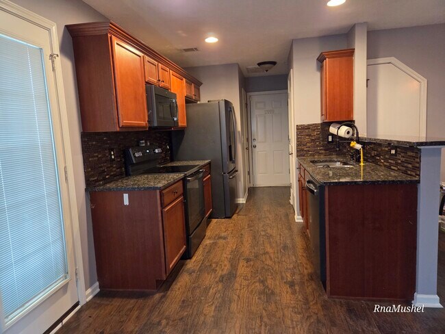 Cocina con encimeras de granito y electrodomésticos de acero inoxidable negros. - 330 Sarna Dr