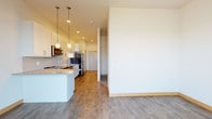 Located at 3601 Cross Hill Dr in Madison, Wisconsin, this single-floor unit offers a clean, contemporary design with a thoughtful open layout. The kitchen is a standout feature, showcasing crisp white cabinetry, speckled granite countertops, and a classic white subway tile backsplash. Stainless steel appliances — including a range, microwave, and dishwasher — provide a polished, modern finish, while pendant lighting over the peninsula adds warmth and style. The peninsula itself creates a natural division between the kitchen and the open living area, which benefits from a bright, airy feel with neutral white walls and durable wood-look flooring that flows seamlessly throughout the space. The living area offers generous room to furnish and personalize, with recessed lighting complementing the overall brightness. A dedicated bedroom provides a quiet retreat with the same consistent flooring and clean wall finishes. The bathroom is well-appointed with a granite-topped vanity, white cabinetry with brushed nickel hardware, and a tub/shower combination, maintaining the cohesive, modern aesthetic found throughout the unit. Overall, this space presents a fresh, move-in-ready environment with consistent finishes and a functional, open-concept design.