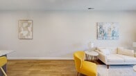 This thoughtfully designed 1-bedroom, 1-bathroom residence at The Landing offers a functional and stylish single-floor layout. The open-concept living, dining, and kitchen area serves as the heart of the home, featuring warm wood-style flooring that flows seamlessly throughout. The kitchen is equipped with stainless steel appliances — including a refrigerator, range, and built-in microwave — complemented by rich, medium-toned cabinetry and granite countertops. A central island with an undermount sink and pendant lighting above provides casual seating and additional prep space, making it ideal for both cooking and entertaining. The living room is bright and welcoming, with recessed lighting, neutral walls, and windows that allow natural light to fill the space. A glass-paneled door offers outdoor access and additional brightness. The spacious bedroom features large windows with exterior views, creating an airy retreat. The bathroom includes dark wood cabinetry with granite countertops, maintaining a consistent design language. A dedicated in-unit laundry room houses a full-size front-loading washer and dryer with overhead shelving for added storage. Clean lines, neutral tones, and modern finishes combine to create a cohesive and comfortable living environment throughout.
