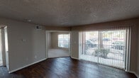 Located at 3440 E Rosemeade Pkwy in Dallas, Texas, this single-story unit offers a practical and well-appointed layout designed for comfortable everyday living. The main living area is expansive and open, showcasing rich, dark wood-style flooring that extends throughout the common spaces. Large sliding glass doors fitted with vertical blinds flood the living room with natural light and provide views of the surrounding greenery. A pass-through opening connects the living area to the kitchen, enhancing the sense of openness. The galley-style kitchen is well-equipped with dark wood cabinetry, granite-style countertops, a black refrigerator, and a ceiling fan overhead. A utility area is accessible directly from the kitchen. The bedrooms feature neutral-toned carpet, ceiling fans, and generously sized windows that bring in natural light and outdoor views. The bathroom is outfitted with dark wood vanity cabinetry, granite-style countertops, a large mirror with overhead lighting, and textured walls that complement the overall aesthetic. Throughout the unit, textured ceilings, neutral wall tones, and white trim create a cohesive and clean interior palette. The layout flows intuitively, making efficient use of the available space.