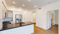 Located at 36101 Inland Valley Drive in Wildomar, California, this efficiently designed single-story, one-bedroom, one-bathroom unit offers a clean, modern aesthetic throughout. The open-concept kitchen and living area serves as the heart of the space, anchored by a striking island with dark marble-veined countertops and a matte black sink fixture. The kitchen is fully equipped with stainless steel appliances, including a French door refrigerator with water dispenser, a range, an over-the-range microwave, and a dishwasher. Crisp white cabinetry extends to the ceiling, complemented by a white geometric tile backsplash, providing ample storage. Warm-toned luxury vinyl plank flooring flows throughout the main living areas, creating a cohesive and inviting atmosphere. Recessed lighting illuminates the kitchen and living space, while the living area benefits from natural light through windows with blinds. The bedroom is a comfortable, well-proportioned room featuring a ceiling fan, a window with outdoor views, and the same warm flooring. A dedicated hallway leads to the bathroom and a closet with louvered doors. The attached garage features an automatic opener and offers convenient additional storage or parking. The overall design is bright, modern, and thoughtfully laid out.