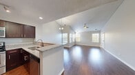 Located at 1856 Michigan Ave in Naperville, IL, this single-story, 3-bedroom, 2-bathroom home offers a well-designed layout with a mix of stylish finishes and practical living spaces. The open-concept living and dining area is a standout feature, highlighted by soaring vaulted ceilings, rich dark hardwood flooring, and abundant natural light streaming through multiple windows. A ceiling fan and a decorative chandelier add both function and character to this central gathering space. The kitchen flows seamlessly into the living area via a peninsula counter topped with granite, complemented by dark cabinetry, stainless steel appliances including a dishwasher and refrigerator, and matching granite countertops throughout. The three bedrooms offer comfortable proportions, with the spacious primary bedroom providing generous room to accommodate furnishings. The bedrooms feature neutral carpet, textured ceilings, and windows that bring in natural light. The bathrooms are finished with tile flooring, dark wood vanities, and clean white fixtures including a tub-shower combination. A connecting hallway ties the layout together efficiently, and the neutral color palette throughout creates a cohesive, move-in ready aesthetic.