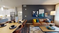 This single-floor residence showcases a thoughtfully designed open-concept layout that seamlessly connects the living, dining, and kitchen areas. The living room serves as a central hub, anchored by a bold dark accent wall that provides a striking contrast to the lighter surrounding walls. Large glass doors invite natural light and offer outdoor access, while wood-style flooring runs throughout, adding warmth and continuity.

The kitchen is well-equipped with white shaker cabinetry extending to the ceiling, granite countertops, a subway tile backsplash, stainless steel appliances, and an island with pendant lighting — offering both function and style. The dining area sits adjacent, comfortably accommodating a full table and chairs.

Each bedroom is generously proportioned, featuring large windows with natural light, ceiling fans, and wood-style flooring. The primary bedroom connects to a spacious en-suite bathroom, complete with granite-topped dual vanity, white cabinetry, and a walk-in closet. A secondary full bathroom includes a granite vanity, soaking tub, and shower combination. The overall aesthetic is clean, modern, and cohesive, with consistent finishes carried throughout the entire residence.