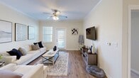 Located at 100 Belmere Luxury Ct in Houma, Louisiana, this well-appointed 2-bedroom, 2-bathroom residence offers a thoughtfully designed single-floor layout that balances comfort and functionality. The open-concept living area welcomes you with warm hardwood-style flooring, crown molding, and a ceiling fan, creating a bright and inviting atmosphere. The kitchen is a standout feature, boasting rich dark-wood cabinetry, granite countertops, stainless steel appliances, a peninsula with pendant lighting, and seamless flow into the adjacent dining area. The dining space is accented by crown molding and hardwood-style flooring, providing an elegant setting for meals. The spacious primary bedroom offers carpeted flooring, a ceiling fan, natural light from a window with shutters, and direct access to a walk-in closet and a private en-suite bathroom. The second bedroom is equally comfortable, also featuring a ceiling fan and its own nearby bathroom complete with a granite-topped vanity, dark cabinetry, a tub-shower combination, and in-unit washer and dryer. Throughout the home, neutral tones and consistent finishes contribute to a clean, cohesive aesthetic.