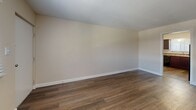 Located at 360 Sandra Ln in Indianapolis, IN, this two-bedroom, one-bathroom unit offers a practical and comfortable single-floor layout. The living room features wood-look flooring, neutral walls, and a window with blinds that allows natural light to fill the space, along with a wall-mounted A/C unit and baseboard heating. The kitchen is well-appointed with rich dark wood cabinetry, granite-style countertops, a stainless steel double sink, and black appliances including a range and dishwasher. A window above the sink provides additional natural light. Both bedrooms are carpeted and feature baseboard heating and window blinds. The primary bedroom includes a ceiling fan with light fixture, while the second bedroom connects through a six-panel white door. The bathroom is clean and functional, featuring a full tub and shower combo with white tile surround and chrome fixtures. A hallway connects the main living areas to the bedrooms and bathroom, contributing to an efficient and easy-to-navigate floor plan. The overall aesthetic is clean and neutral throughout, offering a move-in ready space with consistent finishes.