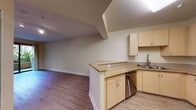 Located at 2389 N Main St in Walnut Creek, California, this single-floor residence offers a thoughtfully designed layout that balances comfort and functionality. The open-concept kitchen is a standout feature, equipped with stainless steel appliances including a range, microwave, and refrigerator, complemented by light wood cabinetry, granite-style countertops, and a peninsula that flows seamlessly into the main living area. Wood-style flooring runs throughout the main living spaces, adding warmth and continuity to the design.

The living area is generously proportioned, bathed in natural light, and opens to a private balcony through large sliding glass doors, offering pleasant views of lush landscaping. A separate room features track lighting and a built-in counter, making it a versatile space suitable for a home office or den.

The bedroom is carpeted for comfort and includes a closet with sliding doors. Corner windows allow abundant natural light and provide views of the surrounding greenery. The bathroom is well-appointed with a granite-topped vanity, wood cabinetry, a full bathtub and shower combination with grab bars, and wood-style flooring. The overall aesthetic throughout the space is clean and neutral, creating a bright, move-in ready environment in the heart of Walnut Creek.