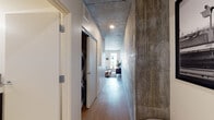Located at 555 12th St in Oakland, CA, this single-floor residence blends industrial aesthetics with contemporary finishes to create a refined urban living experience. The open layout connects key living areas seamlessly, with warm wood-look flooring running throughout to soften the bold architectural elements.

The living area is a standout space, defined by a striking exposed concrete ceiling and a dramatic raw concrete accent wall that serves as a commanding backdrop. Large windows invite abundant natural light and offer views of the surrounding cityscape, while the open layout easily accommodates both lounging and dining areas.

The kitchen is thoughtfully designed with sleek dark cabinetry, white quartz countertops, under-cabinet lighting, a classic subway tile backsplash, and stainless steel appliances — delivering both style and functionality in an efficient galley configuration.

The bedroom offers a calm, intimate retreat with clean white walls, wood flooring, and a cozy, well-appointed layout. The bathroom features a full soaking tub and shower combination, a dark-vanity with a white countertop, and clean tile flooring, maintaining the modern aesthetic found throughout the home.

A hallway with exposed concrete details and a closet with in-unit laundry connections adds to the practical appeal. The cohesive design language — raw materials paired with polished finishes — gives this Oakland residence a distinctly modern, urban character.