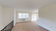 Located at Strathmore Gardens, 48, this single-floor residence offers a thoughtfully designed layout with a blend of practical and updated finishes throughout. The open living and dining area is generously proportioned, finished with neutral-toned wall-to-wall carpeting and bathed in natural light through a large window and sliding glass door fitted with vertical blinds. A chandelier overhead adds a refined touch to the dining area, while baseboard heating and a wall-mounted AC unit ensure year-round comfort.

The kitchen is a standout feature, showcasing rich dark espresso cabinetry paired with granite countertops, a stone tile backsplash, and light ceramic tile flooring. Black stainless appliances — including a gas range, built-in microwave, dishwasher, and refrigerator — complete the space. A window above the counter brings in natural light.

Bedrooms are carpeted and well-sized, each equipped with individual climate control units and ample natural light. One bedroom features a built-in closet with rod and rail storage. A staircase with black metal railing connects to additional areas of the home.

The bathroom is elegantly finished with floor-to-ceiling beige tile, a tub-shower combination enclosed by a sliding glass door, a dark wood vanity, and a bright window.