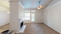 This single-floor residence offers a thoughtfully designed layout that balances comfort and functionality throughout. The kitchen is a standout feature, outfitted with light wood cabinetry, stainless steel appliances including a double wall oven, built-in microwave, smooth cooktop, dishwasher, and a French door refrigerator. A central island provides additional counter space, while rich hardwood-style flooring anchors the room with warmth. A built-in desk area connects the kitchen seamlessly to the rest of the living space. The living room is bright and inviting, highlighted by a classic white-mantled fireplace, a tray ceiling with a ceiling fan, and a glass door opening to an outdoor balcony, allowing natural light to fill the room. Plush carpeting flows throughout the bedrooms, each featuring ceiling fans and windows that offer pleasant outdoor views. The bathrooms are clean and well-appointed — one includes an extended vanity with a large mirror and ample storage, while the other features a tiled soaking tub and shower combination with recessed lighting. A dedicated laundry area with a full-size washer and dryer adds everyday convenience. Overall, the space presents a neutral, move-in-ready aesthetic with practical amenities throughout.