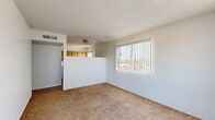 Located at 4201 N 34th Ave in Phoenix, Arizona, this one-bedroom, one-bathroom unit offers a practical and efficient single-floor layout. The living area features warm beige carpeting, a textured ceiling, and a large window fitted with vertical blinds that allows natural light to fill the room while offering views of the surrounding neighborhood. A half-wall partition separates the living space from the kitchen, creating a semi-open feel.

The kitchen is well-equipped with ample honey-toned wood cabinetry both above and below the counters, a white electric range, a full-size refrigerator, a dishwasher, and a double sink. Wood-look flooring runs throughout the kitchen, providing a clean contrast to the carpeted living and sleeping areas.

The bedroom is a comfortable, carpeted space with a window dressed in vertical blinds, providing natural light and ventilation. A dedicated closet and hallway connect the bedroom to the rest of the unit, offering practical storage and flow.

The bathroom features a tub-shower combination, a toilet, and a vanity with a single sink set in a light countertop, complemented by dark wood cabinetry below and a large mirror above. Dark hardwood-style flooring grounds the space with a rich finish. This unit offers a straightforward and functional living environment in a well-connected Phoenix location.