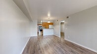 This single-floor residence is designed with an open-concept layout that seamlessly connects the living area to the kitchen, creating a functional and cohesive living environment. Hardwood-style flooring flows consistently throughout the unit, providing a warm, unified aesthetic across all rooms.

The kitchen is equipped with stainless steel appliances, including a range, microwave, and dishwasher. Rich wood-tone cabinetry extends from the lower cabinets to upper shelving, complemented by granite-patterned countertops. A peninsula with pendant lighting above serves as a natural divider between the kitchen and living space, adding both style and practicality.

The living area is generously sized, featuring a sliding glass door that opens to an outdoor patio, allowing natural light to fill the room. A second bedroom also provides direct patio access via a sliding glass door and includes a ceiling fan and a sliding closet. An additional bedroom offers closet storage and connects conveniently to the hallway.

The bathroom features a full tub-shower combination with white tile surround, paired with a wood-tone vanity and granite-patterned countertop. Throughout the unit, neutral gray walls and clean white trim contribute to a bright, move-in-ready atmosphere.