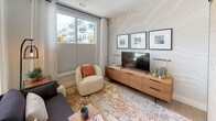 This single-floor residence offers a thoughtfully designed layout that maximizes functionality across its key living spaces. The kitchen is outfitted with stainless steel appliances, including a range, microwave, and dishwasher, complemented by sleek white cabinetry, a marble-style tile backsplash, and light gray countertops. Light wood-style flooring runs underfoot, and a large window with outdoor views fills the space with natural light, with a dining area positioned nearby for convenient everyday living.

The living area continues the bright, airy aesthetic, featuring a textured accent wall and large windows that frame views of the surrounding neighborhood. The space accommodates a comfortable seating arrangement and media setup, creating a relaxed yet stylish environment.

The bedroom features warm golden accent walls paired with neutral tones, plush carpeting, and a closet with double doors, offering a calm and restful retreat. Artwork adds a personalized touch to the space.

The bathroom is finished with light wood-style flooring, white subway tile surrounding the tub and shower combination with a curtain rod, and clean white walls. Framed wall art and a towel rack contribute to a polished, functional design throughout.