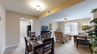 This single-floor unit offers a functional and comfortable layout across two bedrooms and two bathrooms. The open-concept design seamlessly connects the living room, dining area, and kitchen, creating a cohesive and practical flow throughout the space. Warm neutral tones and plush carpeting run throughout the main living areas, contributing to a cozy ambiance.

The living room is generously proportioned, featuring a ceiling fan and a sliding glass door that opens to a private balcony, allowing natural light to filter into the space. The dining area accommodates a full-sized table and sits adjacent to the kitchen, which is configured in a galley style with rich dark wood cabinetry, light granite-toned countertops, a double-basin sink, tile flooring, and black appliances including a refrigerator and range.

The primary bedroom is a well-sized retreat with its own ceiling fan, carpeted flooring, a closet, and direct access to an en-suite bathroom. The second bedroom is similarly appointed with a ceiling fan and natural light from a window. Both bathrooms include a tub-shower combination with tiled surrounds. A dedicated closet provides additional storage within the unit.