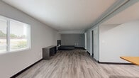 This one-bedroom, two-bathroom unit at 2084 S Hamilton Rd in Columbus, Ohio offers a functional and well-appointed single-floor layout. Throughout the unit, durable light-toned luxury vinyl plank flooring and neutral gray walls create a clean, modern aesthetic complemented by textured ceilings and dark baseboards.

The living room is generously proportioned, featuring a large window that fills the space with natural light and views of the surrounding greenery. The kitchen is fully equipped with warm-toned wood cabinetry, light countertops, and a full suite of black appliances including a refrigerator, gas range, microwave, and dishwasher. A built-in breakfast bar with an attached table provides a convenient dining area directly adjacent to the kitchen.

The bedroom offers a comfortable footprint with recessed lighting and sliding barn-style doors providing access to the space. Two closets offer ample storage throughout the unit. The primary bathroom features an extended wood-toned vanity with a granite-style countertop, a large mirror, and generous drawer storage. The second bathroom includes a full tub and shower combination with accessibility grab bars. A dedicated utility room and additional closet space round out the practical layout of this well-designed unit.