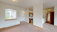 Located at 5420 W Barnes Rd in Spokane, Washington, this two-floor residence offers a practical and well-organized layout designed for comfortable everyday living. The main living area is finished with neutral wall-to-wall carpeting and features a wall-mounted baseboard heating unit, with a window that allows natural light to brighten the space. A door leads out to a balcony or patio area, offering views of the surrounding neighborhood.

The kitchen is designed in a galley configuration, featuring warm-toned oak cabinetry, tile backsplash, light vinyl flooring, and a full suite of white appliances including an electric range, over-the-range microwave, refrigerator, and dishwasher. A double-basin sink with ample counter space completes the kitchen's functional design.

Bedrooms are carpeted and receive natural light through sizable windows, with baseboard heaters providing consistent warmth. The bathrooms are finished with tile flooring, oak vanity cabinetry, a tub-shower combination, and wide mirror panels above the sink.

A dedicated in-unit laundry area accommodates a full-size washer with shelving above, adding everyday convenience. The attached garage provides generous space for vehicle storage along with additional room for belongings. The two-floor layout, captured clearly in the dollhouse view, offers well-defined separation between living and utility spaces.