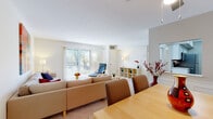 This single-floor residence is designed with a clean, contemporary aesthetic throughout, making efficient use of its well-organized layout. The open-concept living and dining area serves as the heart of the home, where soft carpet underfoot and neutral cream-toned walls create a welcoming atmosphere. The living room benefits from generous natural light streaming through a sliding glass door that opens to an outdoor balcony, offering pleasant outdoor views. A dedicated dining area is positioned adjacent, providing a natural flow ideal for both everyday living and entertaining.

The galley-style kitchen is thoughtfully updated with white shaker cabinetry, light stone-patterned countertops, stainless steel appliances, and warm wood-tone flooring, delivering a functional yet polished workspace. A hallway connects the common areas to the private quarters of the home.

Two carpeted bedrooms offer comfortable retreats, each with windows that admit natural light. One room is configured as a home office, featuring a corner desk and a window with vertical blinds. The full bathroom presents a clean, bright design with white cabinetry, a combined tub and shower, and wood-look flooring. Throughout the residence, the consistent neutral palette and natural light contribute to a calm, livable ambiance.