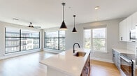 Located at 2307 N Tryon St in Charlotte, NC, this thoughtfully designed two-bedroom, two-bathroom residence offers a seamless blend of modern aesthetics and functional living. Warm hardwood floors extend throughout the entire single-level layout, creating a cohesive and inviting atmosphere.

The open-concept kitchen and living area serves as the heart of the home. The kitchen is equipped with stainless steel appliances, white upper cabinetry, two-tone lower cabinets, a white tile backsplash, and a large central island with a built-in sink and pendant lighting overhead — ideal for both cooking and casual dining.

The living room is bathed in natural light through expansive floor-to-ceiling windows framed in black, offering impressive views of the Charlotte skyline and surrounding neighborhood. A ceiling fan adds comfort to the bright, open space.

Both bedrooms are generously sized, each featuring ceiling fans, large windows with city and neighborhood views, and ample closet space. The primary bedroom is well-proportioned and connects to its own dedicated bathroom.

The two bathrooms reflect a clean, contemporary design. The primary bath features a glass-enclosed walk-in shower with white vertical tile and matte black fixtures, while the second bathroom offers a tiled soaking tub with a shower, also finished with matte black hardware. Both bathrooms continue the home's cohesive, modern aesthetic.