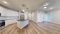 This well-designed 2-bedroom, 2-bathroom residence in Leander, TX offers a thoughtful layout with modern finishes throughout. The kitchen is a standout feature, boasting white shaker cabinetry, dark granite countertops, a subway tile backsplash, stainless steel appliances including a gas range and French door refrigerator, and a central island with globe pendant lighting — ideal for cooking and entertaining. Light wood-style flooring flows through the main living areas, complementing the bright, neutral palette.

Both bathrooms are finished with white vanity cabinetry, dark granite countertops, and large mirrors. One bathroom includes a walk-in marble-tiled shower, while the second features a marble-surround soaking tub and shower combo. The generously sized primary bedroom includes plush carpet, direct access to its en-suite bathroom, and a spacious walk-in closet with built-in shelving and hanging rods. The second bedroom offers comfortable carpeted flooring and clean neutral walls.

A private balcony extends the living space outdoors, offering views of the landscaped community grounds, pool area, and open green space. The exterior presents a clean, contemporary aesthetic with crisp white finishes and modern architectural lines.
