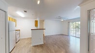 This thoughtfully designed 2-bedroom, 2-bathroom residence offers a comfortable and functional single-floor layout. The open-concept kitchen and living area serves as the heart of the home, featuring warm hardwood-style flooring, crown molding, and a ceiling fan that enhances airflow throughout. The kitchen is equipped with honey-toned cabinetry, granite-style countertops, white appliances, and a peninsula breakfast bar that seamlessly connects to the living space. Sliding glass doors in the living area open to a private balcony overlooking lush, mature trees, flooding the interior with natural light.

Both bedrooms are carpeted for comfort and include ceiling fans and dedicated closets. The primary bedroom offers a walk-in closet with wire shelving for ample storage, while additional closets throughout the unit provide generous organizational space. Each bathroom is finished with white cabinetry, granite-style countertops, a large vanity mirror, and a shower-tub combination with hardwood-style flooring for a clean, cohesive look.

The overall ambiance is bright and neutral, with white walls and trim creating a fresh, inviting atmosphere throughout. The layout flows naturally from room to room, making efficient use of the well-proportioned floor plan.