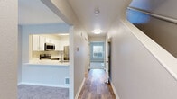 This two-floor residence is designed with a clean, neutral palette and a functional layout that flows naturally from room to room. The kitchen serves as a focal point on the main level, featuring white shaker-style cabinetry, bright white countertops, and a full suite of stainless steel appliances including an electric range, over-the-range microwave, dishwasher, and refrigerator. A peninsula with an undermount sink and brushed gold faucet opens toward the adjacent living area, enhancing connectivity between spaces. Wood-look flooring runs through the main hallway and kitchen, providing a warm, durable foundation underfoot.

A central hallway connects the main living areas, with flush-mount lighting overhead and direct access to a bedroom at the end of the corridor. The bedrooms are carpeted and feature neutral wall tones, natural light from blinds-fitted windows, baseboard heating, and sliding panel closets offering generous storage. One bedroom includes an en-suite bathroom connection, while the bathrooms throughout are outfitted with white vanity cabinetry, white countertops, wood-look tile flooring, and brushed nickel fixtures and accessories. The overall ambiance is bright, clean, and move-in ready.