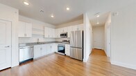 Located at 2375 E 104th Ave in Thornton, CO, this well-appointed one-bedroom, one-bathroom unit offers a thoughtfully designed single-floor layout with modern finishes throughout. The kitchen is a standout feature, showcasing white shaker cabinetry, granite countertops, a full suite of stainless steel appliances including a refrigerator, range, microwave, and dishwasher, and warm wood-style flooring that extends seamlessly into the living areas. Recessed lighting illuminates the space, adding a clean, contemporary feel. The open layout connects the kitchen to the living room, which benefits from natural light and continues the wood-style flooring. The spacious bedroom features plush carpeting, a ceiling fan, and a window with views of the surrounding neighborhood, offering a comfortable and restful retreat. A walk-in closet with wire shelving provides ample storage. The bathroom is finished with a granite-topped vanity with an undermount sink, white subway tile surrounding the tub/shower combo, and matching wood-style flooring. Additional conveniences include a dedicated laundry area, a utility room, and a hallway connecting the living spaces. Clean neutral walls and consistent finishes create a cohesive, move-in-ready environment throughout.