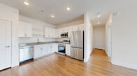 Located at 2375 E 104th Ave in Thornton, CO, this well-appointed one-bedroom, one-bathroom unit offers a thoughtfully designed single-floor layout with modern finishes throughout. The kitchen is a standout feature, showcasing white shaker cabinetry, granite countertops, a full suite of stainless steel appliances including a refrigerator, range, microwave, and dishwasher, and warm wood-style flooring that extends seamlessly into the living areas. Recessed lighting illuminates the space, adding a clean, contemporary feel. The open layout connects the kitchen to the living room, which benefits from natural light and continues the wood-style flooring. The spacious bedroom features plush carpeting, a ceiling fan, and a window with views of the surrounding neighborhood, offering a comfortable and restful retreat. A walk-in closet with wire shelving provides ample storage. The bathroom is finished with a granite-topped vanity with an undermount sink, white subway tile surrounding the tub/shower combo, and matching wood-style flooring. Additional conveniences include a dedicated laundry area, a utility room, and a hallway connecting the living spaces. Clean neutral walls and consistent finishes create a cohesive, move-in-ready environment throughout.