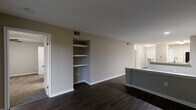 Located at 8720 Knickerbocker Way in Indianapolis, Indiana, this single-floor, three-bedroom, two-bathroom home offers a well-designed layout with a comfortable and modern feel throughout. The combined kitchen and living area serves as the heart of the home, featuring dark hardwood-style flooring, granite countertops, rich dark cabinetry, and a full suite of stainless steel appliances including a refrigerator, range, microwave, and dishwasher. A peninsula counter provides a natural division between the kitchen and living space. The living room is highlighted by built-in wall shelving, ideal for display or storage, and sliding glass doors that open to a private balcony with lush outdoor views. The three bedrooms are carpeted for comfort, each equipped with ceiling fans. The generously sized primary bedroom includes a walk-in closet with wire shelving and direct access to a private en-suite bathroom. The bathrooms feature wood-toned vanities with white countertops and wood-look flooring. Two hallways connect the spaces efficiently, and two closets provide additional storage throughout. The neutral color palette and clean finishes create a cohesive, move-in-ready atmosphere.