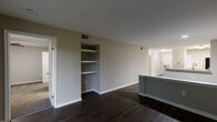 Located at 8720 Knickerbocker Way in Indianapolis, Indiana, this single-floor, three-bedroom, two-bathroom home offers a well-designed layout with a comfortable and modern feel throughout. The combined kitchen and living area serves as the heart of the home, featuring dark hardwood-style flooring, granite countertops, rich dark cabinetry, and a full suite of stainless steel appliances including a refrigerator, range, microwave, and dishwasher. A peninsula counter provides a natural division between the kitchen and living space. The living room is highlighted by built-in wall shelving, ideal for display or storage, and sliding glass doors that open to a private balcony with lush outdoor views. The three bedrooms are carpeted for comfort, each equipped with ceiling fans. The generously sized primary bedroom includes a walk-in closet with wire shelving and direct access to a private en-suite bathroom. The bathrooms feature wood-toned vanities with white countertops and wood-look flooring. Two hallways connect the spaces efficiently, and two closets provide additional storage throughout. The neutral color palette and clean finishes create a cohesive, move-in-ready atmosphere.