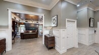 Located at 6690 Hauser Rd in Macungie, PA, this generously sized single-floor facility offers an impressive array of amenities across a thoughtfully designed layout. The entrance welcomes visitors with soaring ceilings, detailed crown molding, white wainscoting panels, and light hardwood flooring — setting an elegant tone that carries throughout the space.

The lounge and sitting areas feature warm, neutral tones with built-in shelving, large windows that bring in natural light, and curated décor that creates an inviting, comfortable atmosphere. French doors and open archways connect rooms seamlessly, promoting a smooth flow throughout.

The kitchen is well-equipped with dark cabinetry, granite countertops, and modern appliances, making it suitable for providing refreshments and serving a variety of needs.

Two distinct fitness areas cater to active use: one features a wood-planked ceiling, large windows overlooking lush greenery, and cardio and strength equipment, while a second offers mirrored walls, ceiling fans, and additional workout machines. A standout feature is the full-size indoor basketball court, complete with a regulation hoop, padded red safety walls, and a rich hardwood floor — an exceptional amenity that elevates the overall offering of this versatile facility.
