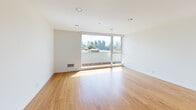 This two-story, two-bedroom, two-bathroom residence at 703 Bellevue Ave E in Seattle's Capitol Hill neighborhood offers a clean, modern aesthetic spread across two well-proportioned floors. The main level features an open-plan kitchen and living area with warm bamboo hardwood flooring and large floor-to-ceiling windows that flood the space with natural light and frame striking views of the Seattle skyline. The kitchen is outfitted with sleek gray upper cabinetry, light wood lower cabinets, dark countertops, white tile backsplash, stainless steel appliances including a refrigerator and dishwasher, and a central island with a butcher block top. Both bedrooms are generously sized, each featuring oversized windows—one overlooking lush treetops and another capturing city views—with plush striped carpet flooring and ceiling fans for comfort. The two bathrooms are finished in a crisp, minimalist style, with one featuring a full soaking tub surrounded by white tile and a warm wood vanity with gray countertop. Hallways and staircases connect the floors seamlessly, with a dedicated closet providing additional storage. The overall ambiance is light, airy, and contemporary, making excellent use of natural light throughout.