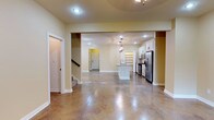 This two-story space offers a thoughtfully designed layout that balances open living with functional private areas. The main level showcases a expansive open-concept living and dining area, distinguished by gleaming polished concrete floors that lend an upscale, modern character to the warm, neutral-toned interiors. Recessed lighting and ceiling fans maintain a bright and comfortable atmosphere throughout.

The kitchen is a standout feature, outfitted with crisp white raised-panel cabinetry, granite countertops, a tile backsplash, and a full suite of stainless steel appliances including a gas range, built-in microwave, and a side-by-side refrigerator. A central island provides additional prep and seating space, while a walk-in pantry adds generous storage. A conveniently located half bath on the main level features a bold dark granite vanity top with a vessel-style sink.

A dedicated laundry room with upper cabinetry, a granite-topped utility cabinet, and exterior door access adds practical convenience. The upper level includes well-sized bedrooms with wood-look laminate flooring, walk-in closets, and warm yellow-toned walls. Full bathrooms on the upper level feature granite vanities, tile flooring, and shower-tub combinations, completing this functional and stylish space.