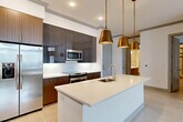 Located in Atlanta's vibrant Midtown neighborhood, this well-appointed 1-bedroom, 1-bathroom residence offers a thoughtfully designed open-concept layout with modern finishes throughout. Light-toned hardwood-style flooring spans the entire space, lending a clean and cohesive aesthetic. The open kitchen and living area serves as the heart of the home, centered around a sleek white quartz island with an undermount sink and integrated dishwasher. Striking brass pendant lights hang above the island, adding warmth and visual interest. The kitchen features two-tone cabinetry — rich walnut lower cabinets paired with high-gloss dark upper cabinets — complemented by stainless steel appliances including a side-by-side refrigerator, gas range, and built-in microwave. The living area is bright and airy, benefiting from large windows with urban views and a private exterior door. The bedroom is a comfortable retreat with natural light from a dedicated window. The full bathroom is elegantly finished with marble-look tile, a wood-toned vanity with quartz countertop, and a soaking tub with tiled surround. A dedicated closet completes this efficiently designed residence.