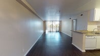 Located along E San Carlos Street in San Jose, California, this single-story unit offers a well-organized layout across a comfortable footprint. Dark hardwood-style flooring runs throughout the main living areas, creating a cohesive and polished look that contrasts with the neutral-toned walls.

The living area is notably spacious and open, benefiting from a large sliding glass door that leads to a balcony and allows generous natural light to fill the room. A ceiling fan overhead provides additional comfort, and the open sightlines to the kitchen make the space feel connected and functional.

The galley-style kitchen is efficiently arranged, with white cabinetry lining both walls, a stainless steel sink, a full-size refrigerator, an electric range with overhead microwave, and ample counter and storage space. A pass-through counter connects the kitchen to the adjacent living and dining area.

The bedroom features plush carpeting, a mirrored sliding closet with built-in shelving, and a calm, neutral palette. The bathroom includes a single vanity with a wide mirror, under-sink cabinetry, a full tub and shower combination, and the same rich hardwood-style flooring found throughout the rest of the unit.