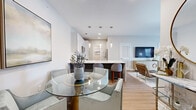 This well-appointed single-floor residence showcases a contemporary design with clean lines and a neutral color palette throughout. The open-concept layout seamlessly connects the living, dining, and kitchen areas, creating a cohesive and functional living space. Light wood-style flooring runs throughout the main living areas, adding warmth and continuity.

The kitchen is a standout feature, equipped with crisp white shaker cabinets, quartz countertops, a subway tile backsplash, and stainless steel appliances including a range, microwave, and dishwasher. A large island with bar seating and pendant lighting above serves as both a prep space and a casual dining spot. The adjacent dining area accommodates a full table, making the space ideal for entertaining.

The living room is bright and inviting, anchored by a ceiling fan and sliding glass doors that open to a private balcony with outdoor views. Two well-sized bedrooms feature plush carpeting, ample natural light from large windows, and ceiling fans. The primary bedroom offers a restful retreat with generous proportions.

Both bathrooms are finished with white vanities, quartz countertops, and tub-shower combinations, reflecting a clean, modern aesthetic. The overall ambiance of this residence is polished, comfortable, and move-in ready.