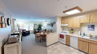 Located at 619 Hartford Road in Manchester, Connecticut, this one-bedroom, one-bathroom residence offers a thoughtfully designed, single-floor layout that maximizes comfort and functionality. The open-concept kitchen and living room form the heart of the home, creating a seamless flow between cooking, dining, and relaxing spaces. The kitchen is outfitted with light maple cabinetry, ample counter space, a full suite of white appliances including a range, dishwasher, and refrigerator, and a skylight-style ceiling fixture that brightens the space. A peninsula counter transitions naturally into a dedicated dining area with room for a table and chairs, all illuminated by a pendant light. The living room features plush carpeting, large windows that invite natural light and outdoor views, and comfortable seating space. The bedroom is a serene retreat with soft carpeting, a window with a decorative valance, and generous room for furnishings. The bathroom includes tile flooring, a shower/tub combination, and practical grab bars, reflecting an accessibility-conscious design. A hallway connects the rooms efficiently, completing this compact yet complete residence.